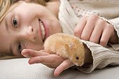 Girl laid down with a hamster in the hand France
