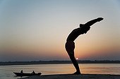 Man in a yoga posture at the edge of the Ganges India