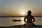 Man in praying yoga posture at the edge of the Ganges India