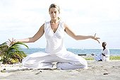 Woman and man praticing yoga on a beach in Martinique Island