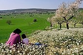 Woman and child in an almond trees field in spring