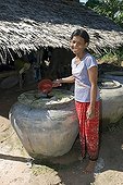 Laughing woman bailing water out of a concrete water tank, Takeo Province, Cambodia