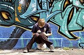 Ten-year-old boy playing with his Nintendo in front of a graffiti wall, Germany, Europe