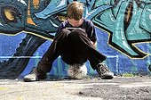 Ten-year-old boy playing with his Nintendo in front of a graffiti wall, Germany, Europe