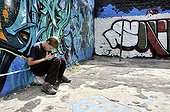 Ten-year-old boy playing with his Nintendo in front of a graffiti wall, Germany, Europe