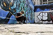 Ten-year-old boy playing with his Nintendo in front of a graffiti wall, Germany, Europe