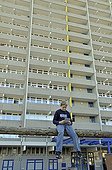 Boy, 9, playing with his Nintendo in front of a high-rise apartment building, satellite town of Chorweiler in Cologne, North Rhine-Westphalia, Germany, Europe