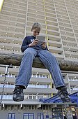 Boy, 9, playing with his Nintendo in front of a high-rise apartment building, satellite town of Chorweiler in Cologne, North Rhine-Westphalia, Germany, Europe