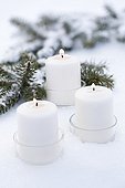 Candles and spruce branche in the snow