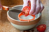 Harvest of tomato seeds ; Taking out tomato seeds with the edge of a knife in a strainer. 