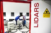 Preparation of a Lidar laser at Maïdo,Observatoire de Physique de l'Atmosphère de la Réunion (OPAR). Reunion Island. Guillaume Payen, OPAR's technical manager, and Nicolas Marquestaut, research engineer, prepare the lasers for the night's shooting. These lidar lasers are designed to analyze certain components of the atmosphere. The Maïdo atmospheric observatory on La Réunion (one of the 3 measurement sites of the OPAR (Observatoire de Physique de l'Atmosphère de La Réunion), has been installed since October 2012 on the Piton Maïdo at an altitude of 2,200 meters. The laboratory is equipped with active and passive remote sensing instrumentation, enabling long-term, high-quality measurements of the vertical profiles of numerous climatic variables. It enables us to monitor atmospheric and climatic parameters in a context of accelerating climate change, and benefits from a unique situation in the tropical southern hemisphere, where observations are extremely rare. The observatory has 4 laser lidars, 2 of which are visible (green), and 2 invisible to the human eye. Three of the lidars are fired vertically, and one at 45 degrees, to measure wind. (i) One lidar is dedicated to measuring water vapour, with a large 1.20 m diameter telescope and two paired lasers. (ii) Three other LIDARS are designed to measure vertical profiles of atmospheric parameters (including one fired at 45 degrees, for wind measurements). The Maido observatory benefits from several major advantages. (1) Its latitudinal position for studying stratospheric transport processes. (2) Its altitude, free from pollution, humidity and light, considerably improves the quality of remote sensing measurements for studying the chemical composition of the atmosphere. OPAR's observations are part of several international observation networks, including NDACC (Network for the Detection of Atmospheric Composition Changes) and GAW (Global Atmospheric Watching).
