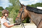 Young woman giving a treat to her horse as a reward