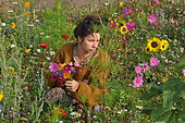 Young woman making a bouquet in a flowered meadow