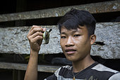 Boy posing with a small bird of the family of sunbirds that he shot with a rifle and that he will eat, Pulau Siberut, Sumatra, Indonesia