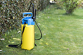 Sprayer placed on the lawn of a garden, before treatment of a hedge in Printemps, Pas de Calais, France