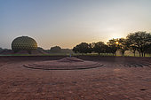 Le Matrimandir et son jardin. Auroville, "la ville de l'Aurore", cité expérimentale, idéale, universelle, est née d'un rêve de Mirra Alfassa, nommée "La Mère", et de Sri Aurobindo. Elle a été inaugurée en 1968, accueille des gens du monde entier, partageant la volonté de réaliser l'unité humaine. Le Matrimandir, cette gigantesque boule dorée est un lieu de méditation pour une nouvelle conscience, et rayonne depuis le centre de la ville. Ici, une salutation du matin devant la sphère.