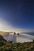 April 12, 2017 - The Southern Cross (Crux), the Pointer Stars (Alpha and Beta Centauri) and the stars of Carina (at top) rising in the moonlit sky over the sea stacks at the eastern end of the Twelve Apostle sea stack formation, on the Great Ocean Road, Victoria, Australia. . The moon, a day past full, is rising off frame at left, brightening the sky and lighting the landscape and seascape.