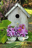 Wooden birdhouse and clay birds as garden decorations, Ginkgo leaves and flower bouquet