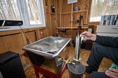 Measuring and checking the sugar content in the syrup, making maple syrup in a sugar shack at sugar time, Saint-Barthélemy, Lanaudière, Quebec, Canada