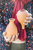Woman holding various models of oyas, or watering jars, to be buried at the foot of crops.