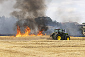 Following a period of extreme heat, a fire ravages a cereal plot: barley in the foreground and wheat in the distance, a tractor pulls a dethatcher to stop the flames. France Damage, loss, danger, insurance, appraisal, compensation problems
