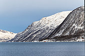Landscape and dwellings amidst fjords and sharp Alpine mountains, the sun is not visible in winter, only the moon illuminates the landscape. Islands around Tromso, Norway
