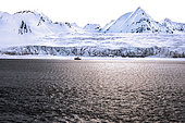 Landscape of Svalbard in Norway, also known as Spitsbergen. This territory stretches from latitude 75 to 80 degrees to the pack ice a few hundred kilometers from the North Pole. Melting ice, early global warming. Front of a glacier fracturing at the edge of a fjord. Explorers' sailboat at the ice edge