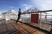 Landscape of Svalbard in Norway, also known as Spitsbergen. This territory stretches from latitude 75 to 80 degrees to the pack ice a few hundred kilometers from the North Pole. Melting ice, premature global warming. Exploration boat in Madeleine Bay. Young explorer on deck.