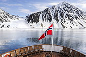Landscape of Svalbard in Norway, also known as Spitsbergen. This territory stretches from latitude 75 to 80 degrees to the pack ice a few hundred kilometers from the North Pole. Melting ice, premature global warming. Exploration boat in Baie de la Madeleine. Norwegian flag