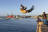 Jeunes plongeurs sautant dans la mer faisant le concours du plus beau saut au Sunset Jump Spot, Stone Town, dans la capitale de Zanzibar en Tanzanie