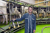 Eleveur et vaches laitières dans une salle de traite, France