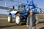 45-year-old farmer smiling in a field in front of his self-propelled sprayer, France