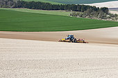 Tracteur attelé à l'avant et l'arrière de herses rotatives et scarificateurs prépare une terre fine pour les semis de précision, grande culture sur sol limoneux calcaire, dans un paysage de la Marne, France