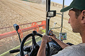 Farmer at the wheel of his claas harvester in barley, monitoring his cutting line on video, a calculator gives real-time yield and grain loss. France
