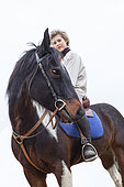 Rider riding an appaloosa horse in a meadow in winter