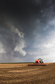 Sowing oilseed rape, wheat or barley with a large-width Vaderstadt seed drill using a simplified no-till technique, under stormy skies in late summer, France.