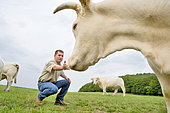 Young farmer with his herd of Charolais cows in the pasture, France