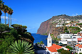 The church of the village of Camara de Lobos with the cliffs of Cabo Girao, the highest of the island. Madeira island. Portugal.
