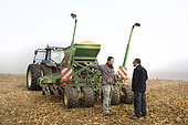 Farmer giving advice to his worker before direct seeding with his John Deere seeder on maize stubble after harvest. TCS. France