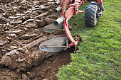 Plowing, turning over a meadow with a tractor pulling a reversible plow. plow, symbolic tool of agriculture, France