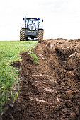 Plowing, turning over a meadow with a tractor pulling a reversible plow. plow, symbolic tool of agriculture, France