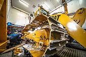 A mechanic maintains the Caterpillar loader in one of Concordia's two garages. This Caterpillar loader is the only vehicle capable of operating during the winter period, as its tracks are made of metal, not polymer; plastic tracks crack under such temperatures. This loader is mainly used to supply the station with drinking water: every week, the mechanic removes a few buckets of snow which he then deposits in the melter, a kind of large tank heated by the residual heat from the power station's engine. Concordia Antarctic Research Station, Dome C plateau, East Antarctica.