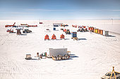 The Raid vehicles park close to the station, then start unloading the containers. The containers are then pulled along the ground to their final unloading location. Concordia Antarctic Research Station, Dome C plateau, East Antarctica.