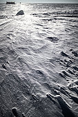 The floor of the Dome C plateau where the Concordia station is located is shaped by the wind. A scientific laboratory containing measuring instruments can be seen in the background. Concordia Antarctic Scientific Research Station, Dome C plateau, East Antarctica.