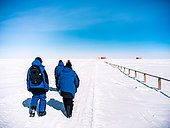 Three scientists walk to their laboratory. Concordia Antarctic Research Station, Dome C plateau, East Antarctica.