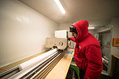 Two scientists cut and pack ice cores. Here, they cut each core lengthwise. Concordia Antarctic Research Station, Dome C plateau, East Antarctica.