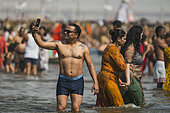 Kumbh Mela 2025: The Sacred Goes Viral. A Sacred Selfie at the Sangam. A Man Smiling and Taking a Selfie in the Sacred Waters of the Sangam. In the holy waters of the Sangam, a man smiles with joy as he captures a selfie, documenting his personal connection to the sacred rivers of the Kumbh Mela. The serene waters of the confluence of the Ganges, Yamuna, and the mythical Sarasvati flow around him, symbolizing the purity and spiritual significance of this ancient ritual. While the man's smile and the phone in his hand represent the modern age, his immersion in the sacred waters ties him to the centuries-old tradition of pilgrimage and faith. This selfie captures not only a personal moment of devotion but also reflects the harmony between the ancient and the contemporary at the Kumbh Mela.