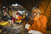 Kumbh Mela 2025: The Sacred Goes Viral. Sadhus Smoking Chilum in Their Tents. Sadhus Relaxing and Smoking Chilum in Their Tents at the Kumbh Mela. Inside their humble tents at the Kumbh Mela, a group of sadhus smoke chilum, a traditional pipe used in their spiritual practice. The chilum, filled with tobacco or cannabis, is often smoked during meditative or ritual moments, connecting the sadhus to higher states of consciousness. As they sit in their tents, surrounded by the sacred atmosphere of the festival, the sadhus remain focused on their spiritual journey. The act of smoking, though often seen as a moment of relaxation, is intertwined with their ascetic lifestyle, where inner peace is sought through solitude, prayer, and reflection. The scene reflects the unique spiritual practices that are part of the rich tapestry of the Kumbh Mela, where devotion takes many forms.