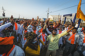 Kumbh Mela 2025: The Sacred Goes Viral. Celebrating at the Kumbh Mela with Devotees Dancing and a Sadhu. Devotees and a Sadhu Dancing and Celebrating at the Kumbh Mela. A joyful scene at the Kumbh Mela where devotees, dressed in white and adorned with orange scarves, celebrate in unison, dancing to the rhythm of spiritual music and chanting. In the center of the crowd, a sadhu dressed as a divine figure, with painted face and long hair, becomes part of the celebration, embodying the spiritual energy that the festival exudes. The lively expressions and movements of the devotees contrast with the more serene aspects of the Kumbh, showing how spirituality and celebration blend at this unique gathering. The image captures a moment of unity, devotion, and joy, as people from all walks of life come together, celebrating their faith and the shared experience of the Kumbh Mela.
