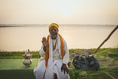 Kumbh Mela 2025: The Sacred Goes Viral. Resting by the Sacred River. As the sun sets over the holy Ganges, a sadhu finds solace by its banks, resting after a day of spiritual practices. In the tranquil moments of solitude, the river reflects the stillness within, a pause in the journey of asceticism. The setting sun casts a golden glow, symbolizing the eternal cycle of life and devotion. Here, amidst the chaos of the Kumbh Mela, the sadhu embodies the peace that comes with renunciation, a reminder that even in the most crowded places, moments of inner calm are attainable.